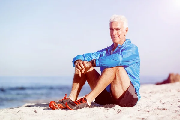 Homme en tenue de sport assis à la plage Photos De Stock Libres De Droits