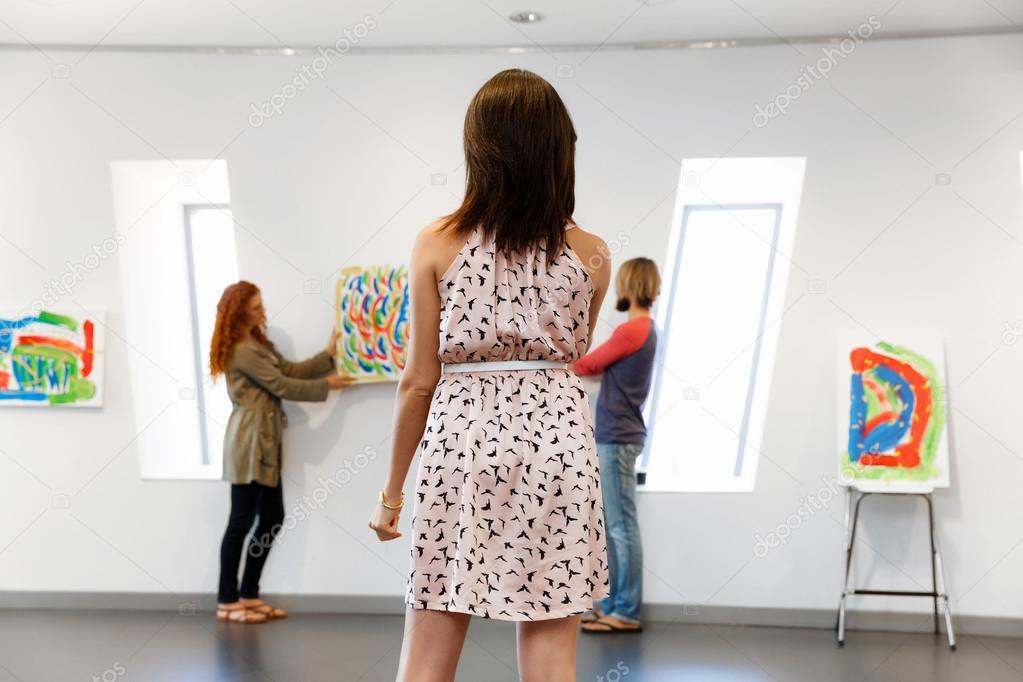 Young artists in gallery hanging painting on walls — Stock Photo