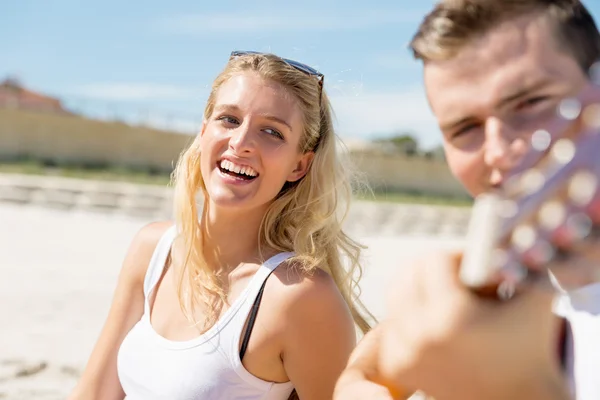 Pareja joven tocando la guitarra en la playa enamorada —  Fotos de Stock