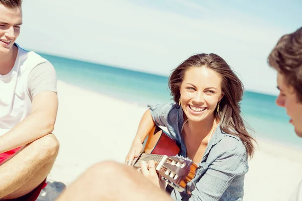 美丽的年轻女子在海滩上弹奏吉他 — 图库照片