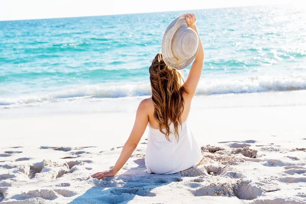 Genç bir kadın sahilde oturuyor. — Stok fotoğraf