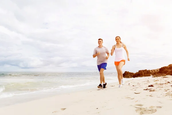 Бігуни. Молода пара біжить на пляжі — стокове фото