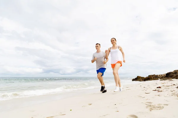 Des coureurs. Jeune couple courant sur la plage — Photo