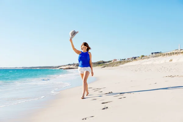 Jeune femme marchant le long de la plage — Photo