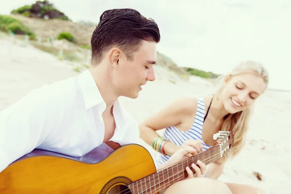Jovem casal tocando guitarra na praia no amor — Fotografia de Stock