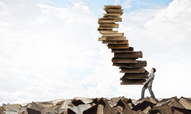 Adam elinde kitap yığını ile