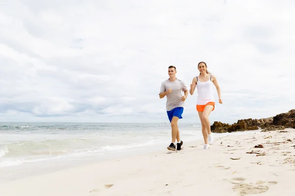 Бігуни. Молода пара біжить на пляжі — стокове фото