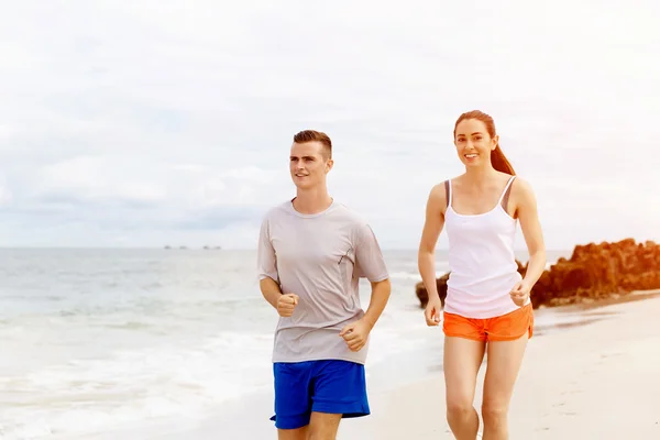 Corredores. Pareja joven corriendo en la playa —  Fotos de Stock