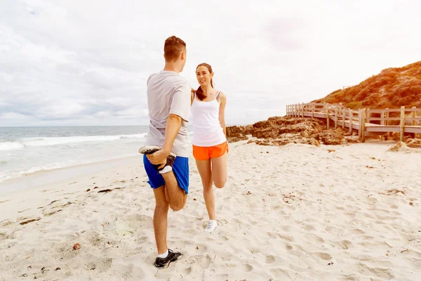 Löpare. Ungt par utövar och stertching på stranden — Stockfoto