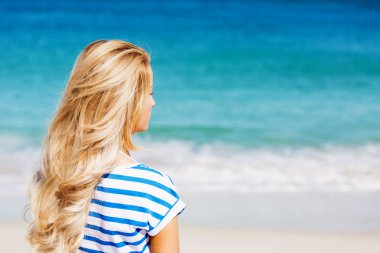 Genç bir kadın sahilde dinleniyor.