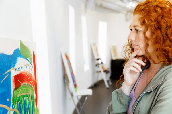 Mujer joven caucásica en la galería de arte frente a las pinturas —  Fotos de Stock