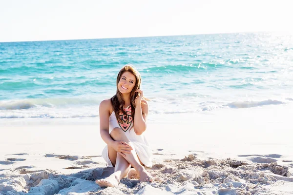 Jonge vrouw zittend op het strand — Stockfoto