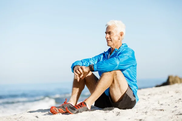 Adam sahilde otururken spor giyim — Stok fotoğraf