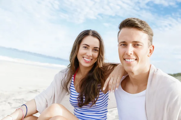Romantische jonge paar zittend op het strand — Stockfoto
