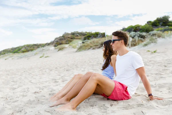 Romantico giovane coppia seduta sulla spiaggia — Foto Stock