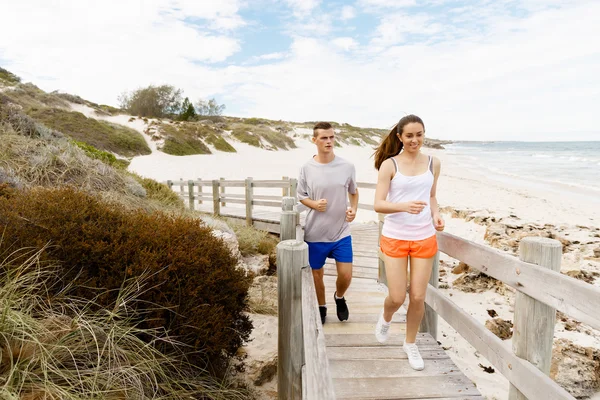 Des coureurs. Jeune couple courant sur la plage — Photo