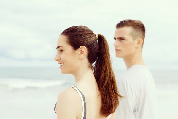 Pareja joven buscando reflexivo mientras están de pie uno al lado del otro en la playa — Foto de Stock