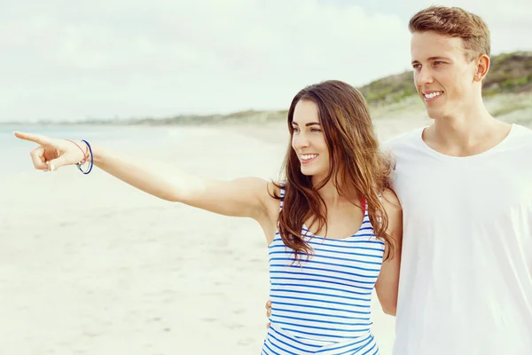 Gelukkige jonge man en vrouw paar samen wandelen op een strand — Stockfoto