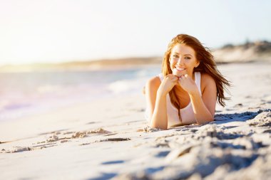 Genç bir kadın sahilde dinleniyor.