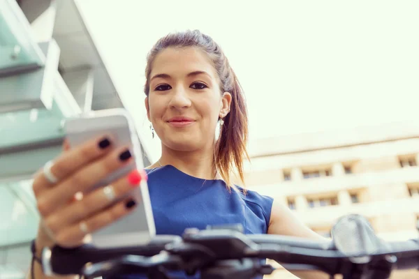 Jonge vrouw woon-werkverkeer op fiets houden een mobiele — Stockfoto