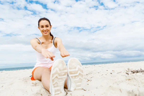 Mujer joven entrenando en la playa afuera — Foto de Stock