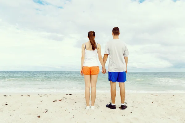 Pareja joven buscando reflexivo mientras están de pie uno al lado del otro en la playa — Foto de Stock