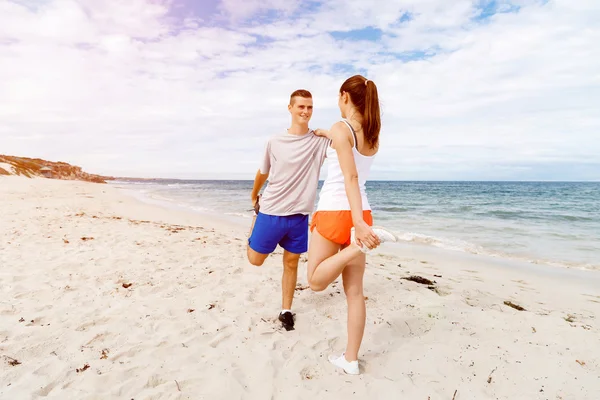 Des coureurs. Jeune couple exerçant et stertching sur la plage — Photo