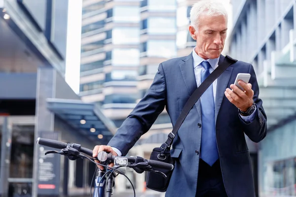 Successful businessman on bicycle with mobile phone — Stock Photo, Image