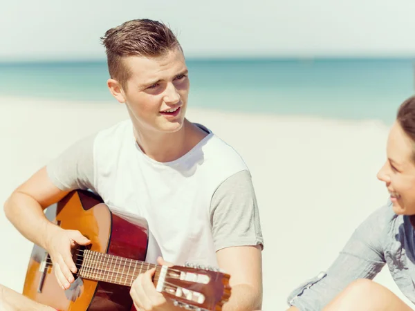 Schöne junge Leute mit Gitarre am Strand — Stockfoto