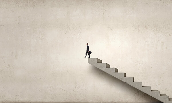 Young businessman walking up on staircase representing success concept