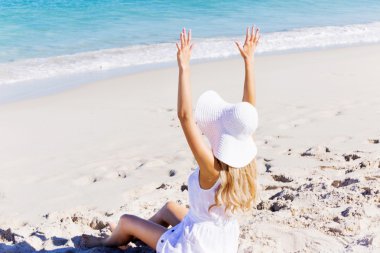 Genç bir kadın sahilde dinleniyor.