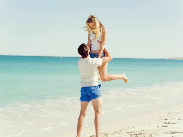 Casal feliz pulando em férias na praia — Fotografia de Stock