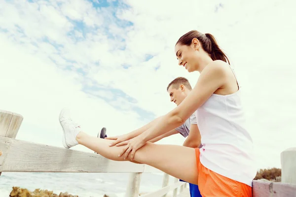 Runners. Young couple exercising and stertching on beach — Stock Photo, Image