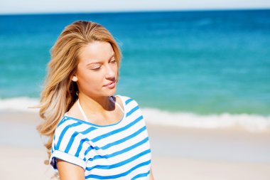 Genç bir kadın sahilde dinleniyor.