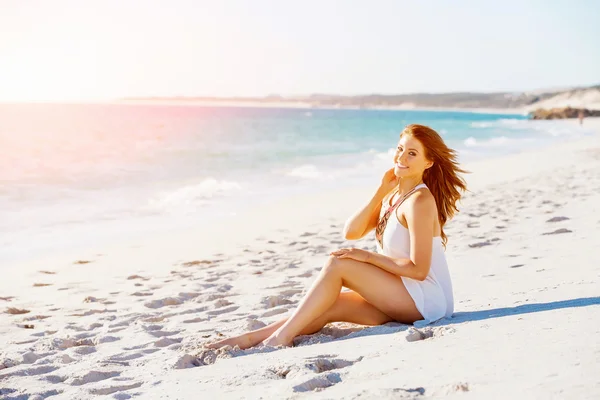 Ung kvinna sitter på stranden — Stockfoto