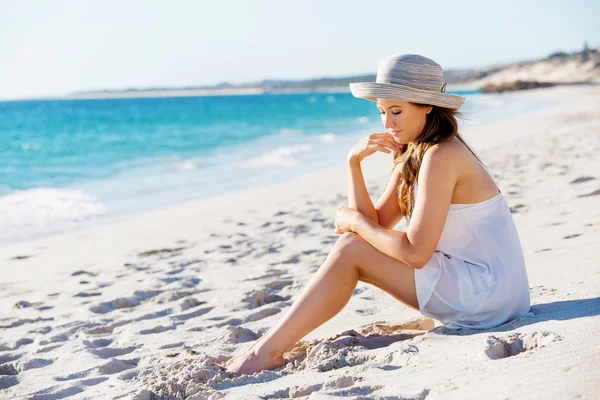 Νεαρή γυναίκα που κάθεται στην παραλία — Φωτογραφία Αρχείου