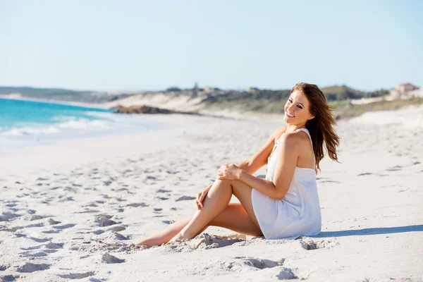 Молодая женщина сидит на пляже — стоковое фото