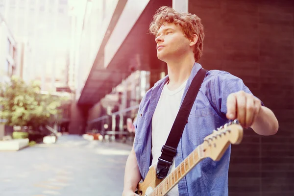 Joven músico con guitarra en la ciudad — Foto de Stock