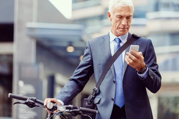 Successful businessman on bicycle with mobile phone — Stock Photo, Image