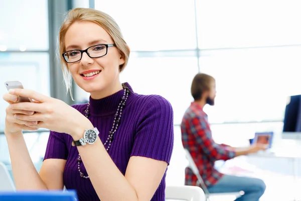 Zakenvrouw in kantoor houden van mobiele telefoon — Stockfoto