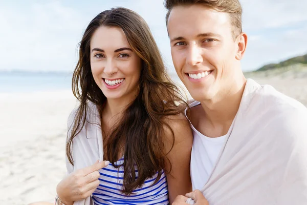 Romantische jonge paar zittend op het strand — Stockfoto