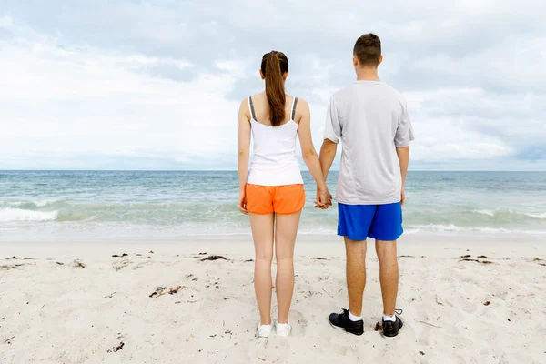 Νεαρό ζευγάρι ψάχνει στοχαστικό ενώ στέκεται δίπλα στην άλλη στην παραλία — Φωτογραφία Αρχείου