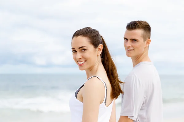 Jong koppel op zoek doordachte terwijl staande naast elkaar op het strand — Stockfoto