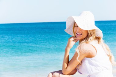 Genç bir kadın sahilde dinleniyor.