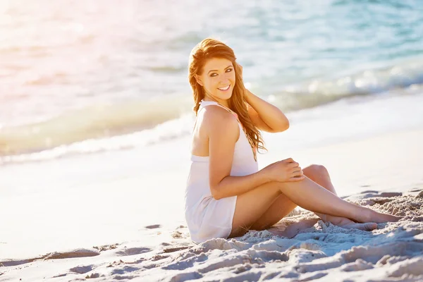 Νεαρή γυναίκα που κάθεται στην παραλία — Φωτογραφία Αρχείου