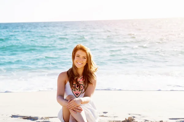 Jonge vrouw zittend op het strand — Stockfoto