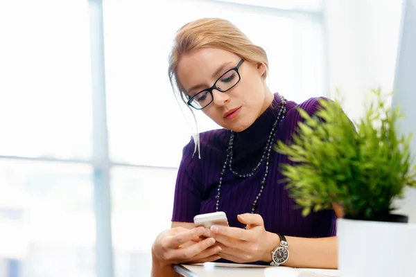 Geschäftsfrau im Büro mit Handy — Stockfoto