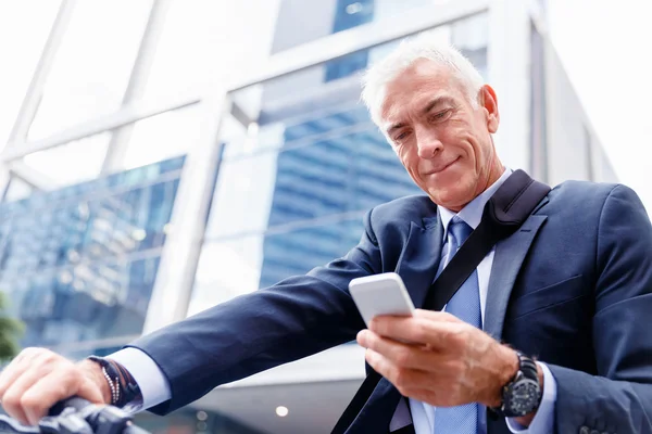 Successful businessman on bicycle with mobile phone — Stock Photo, Image