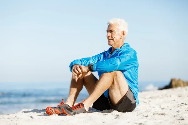 Mannen i sportkläder sitter på stranden — Stockfoto