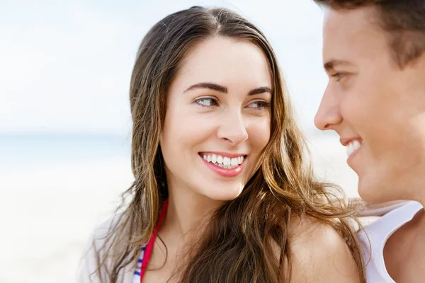 Romantische jonge paar zittend op het strand — Stockfoto